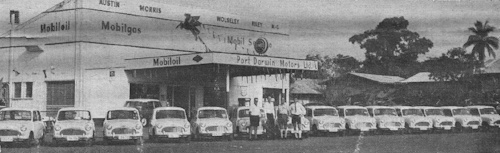 An alternative view of the delivery of 14 Morris 850s outside Port Darwin Motors (The BMC Rosette, March 1964).